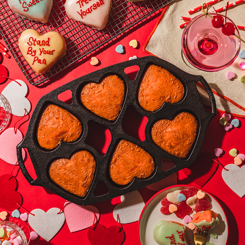 Freshly baked mini heart cakes on a Valentine's Day themed background.