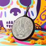 Decorative cast iron skillet with skull design on a colorful abstract background