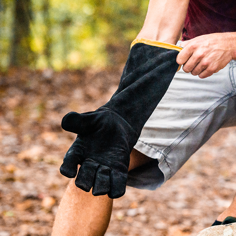 A person putting on black leather gloves is shown in a kneeling position with the gloves on their hands.