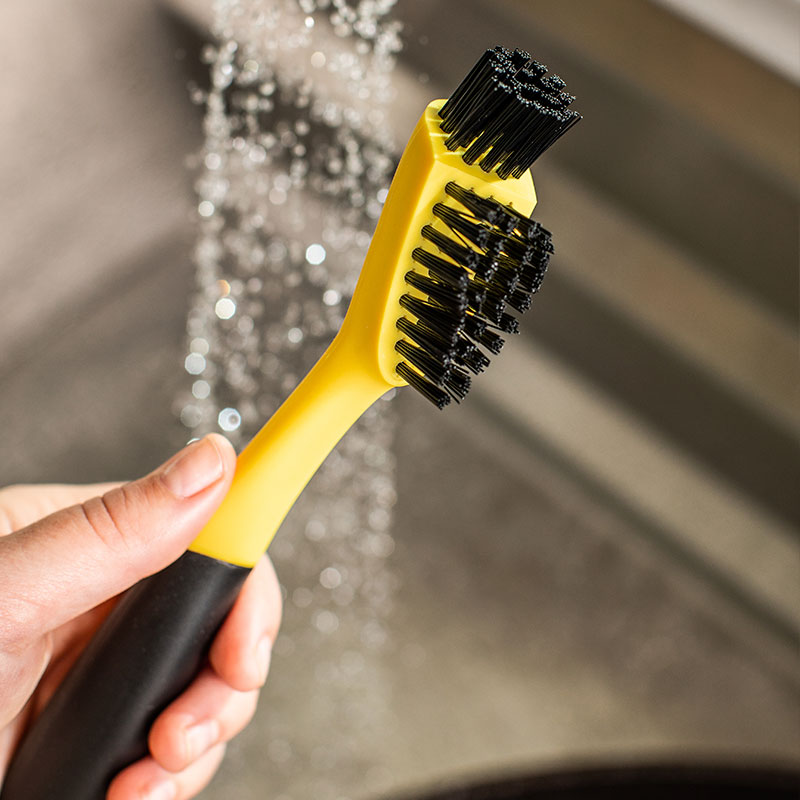 Close-up of someone holding brush in front of running water.
