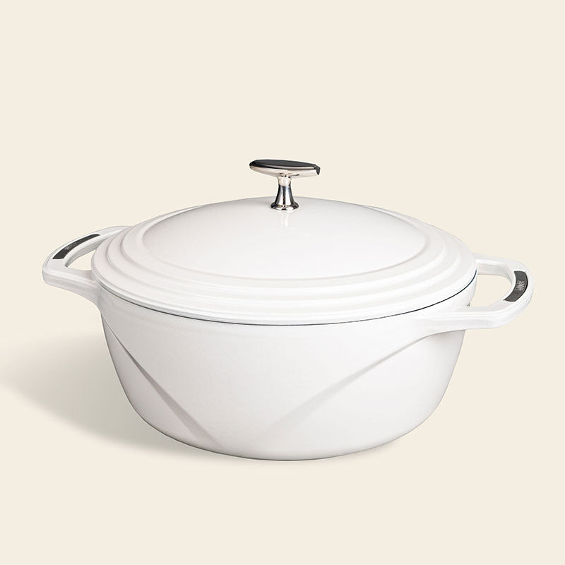 White enameled cast iron Dutch oven with a lid on a white background