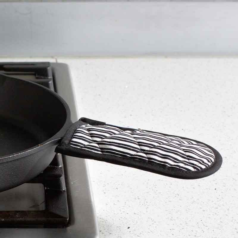 Handle holder being used on skillet on stove.