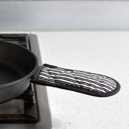 Handle holder being used on skillet on stove.