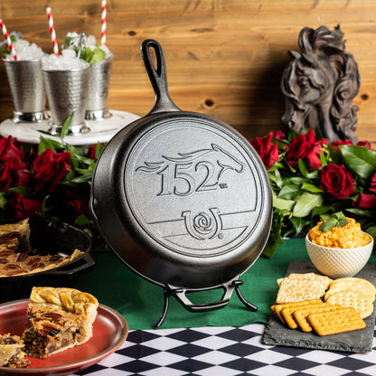 Kentucky Derby skillet, featuring the 152nd year logo, displayed beside mint julep's, roses, and other food.
