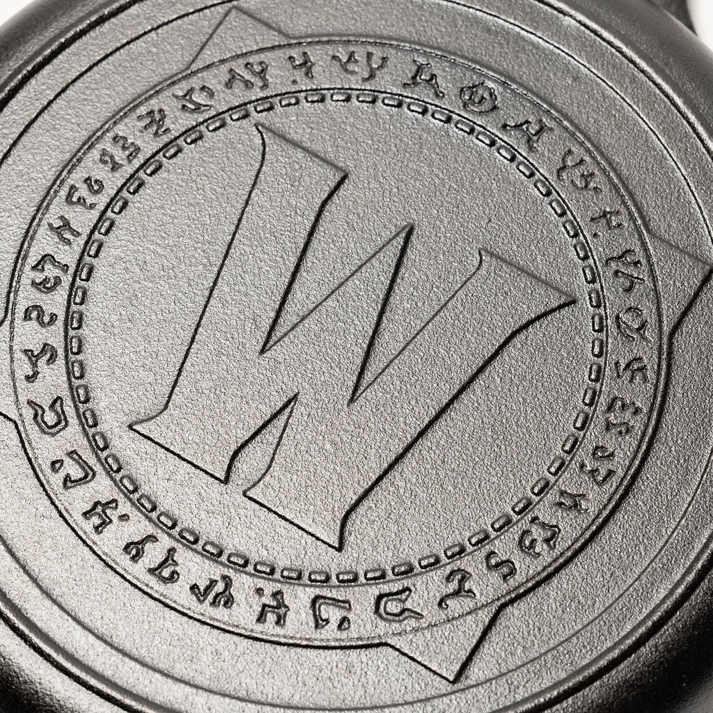 Close-up of World of Warcraft logo on the bottom of a cast iron skillet.
