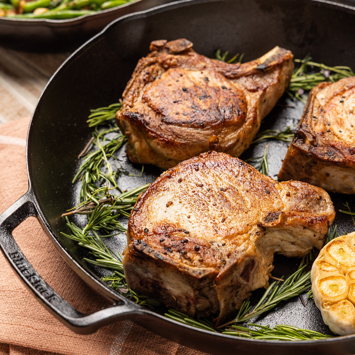 Pork chops, cooked and served in skillet with rosemary.