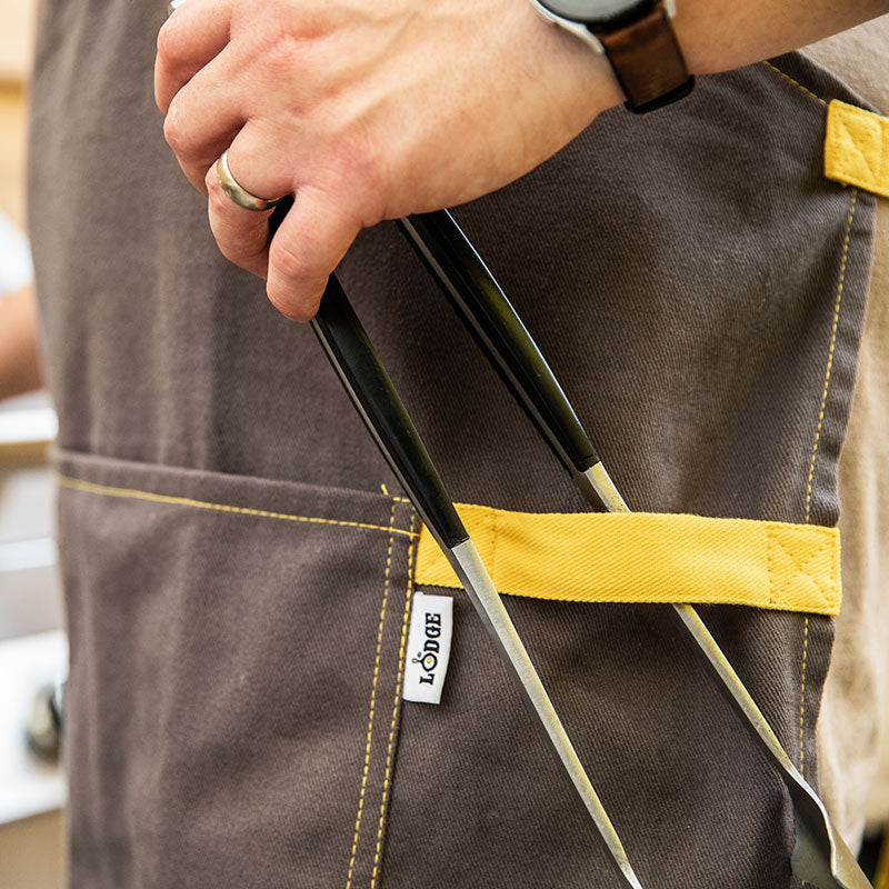 Someone putting tongs on front strap of apron.