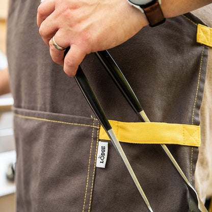 Someone putting tongs on front strap of apron.