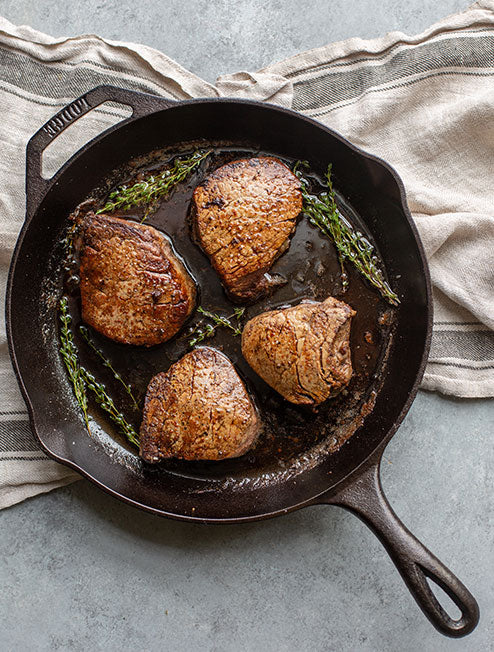 Filet mignon prepared in skillet, served on counter.