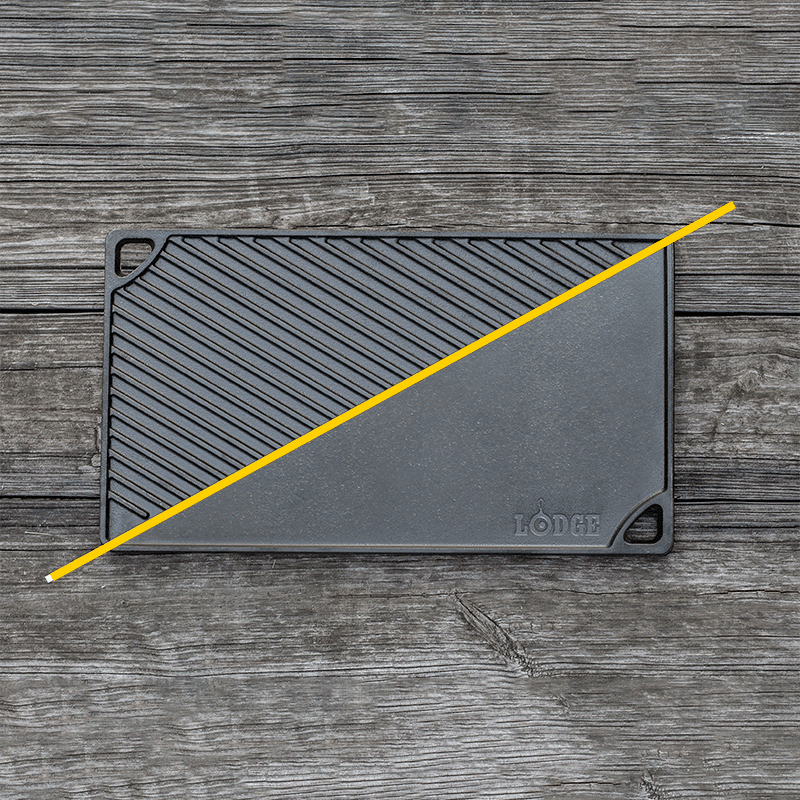 Griddle/grill pan on wood surface with handles on opposite corners.