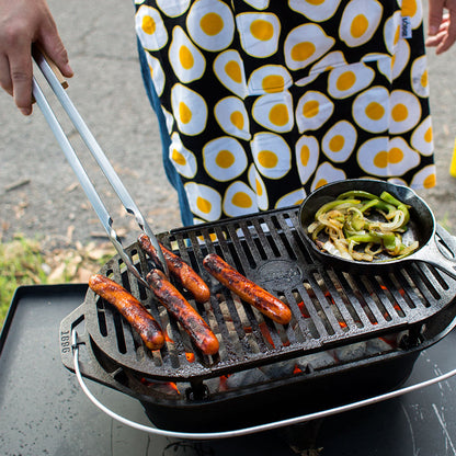 Someone cooking hot dogs on our Sportsman's Pro Grill using tongs.