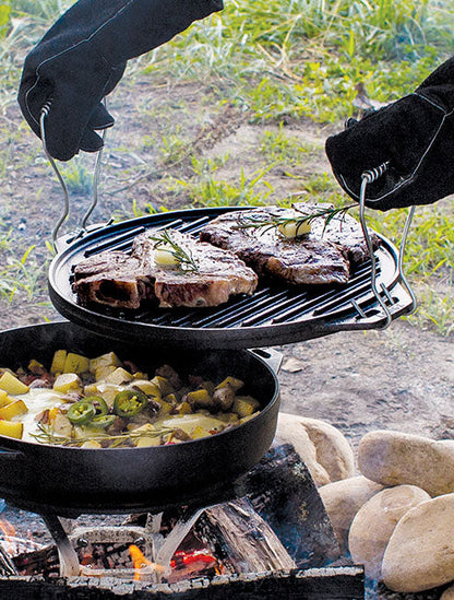 Someone using handles to lift grill pan off of base while cooking steak.