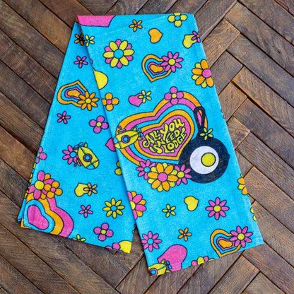 Towel partially unfolded on counter, showing the colorful floral and heart pattern spreads throughout the towel.