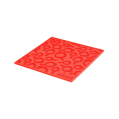 Red silicone trivet with embossed Lodge skillets scattered throughout surface.