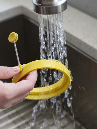 Someone rinsing egg ring in sink.