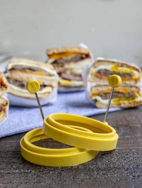 Egg rings in front of freshly made sausage, egg, and cheese biscuits.