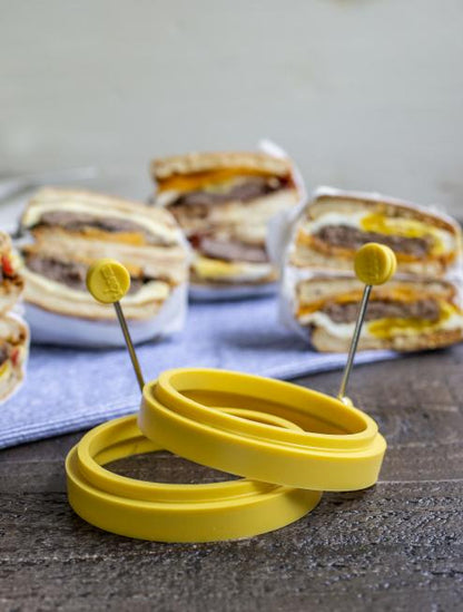 Egg rings in front of freshly made sausage, egg, and cheese biscuits.