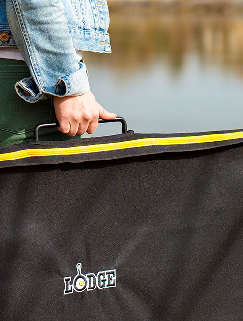 Someone carrying our cooking table with cover near lake.