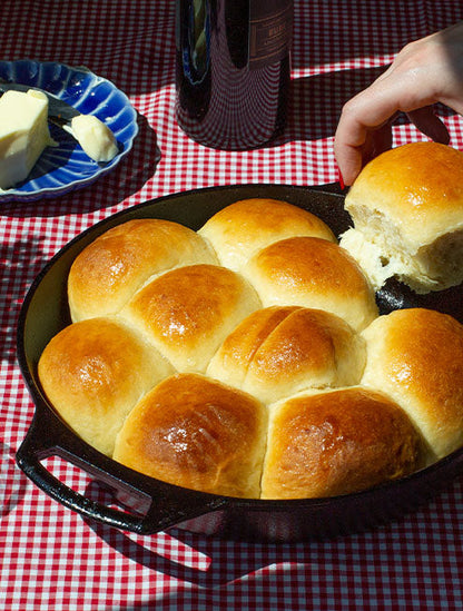 Freshly buttered dinner rolls being taken out of pan.