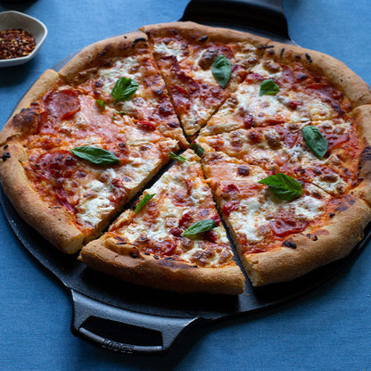 Freshly baked pizza, cut and served on pan garnished with basil.