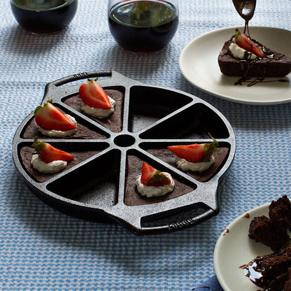 Brownies served and prepared in pan, topped with whipped cream and strawberries.