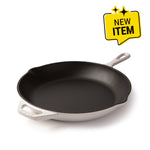 A Lodge enameled cast iron skillet with a black interior and a white exterior, shown on a white background with a yellow 'NEW ITEM' badge in the top right corner.