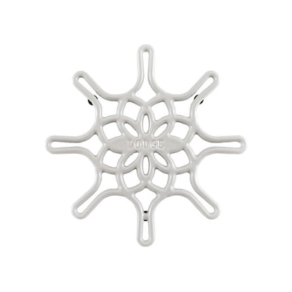 A white enameled cast iron trivet with a geometric snowflake-like pattern.