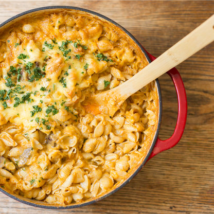 Freshly made macaroni and cheese being served from braiser.