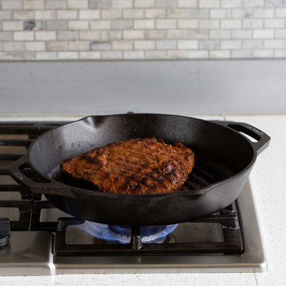 Steak being cooked on stove with pan, shoring the grill lines from pan.