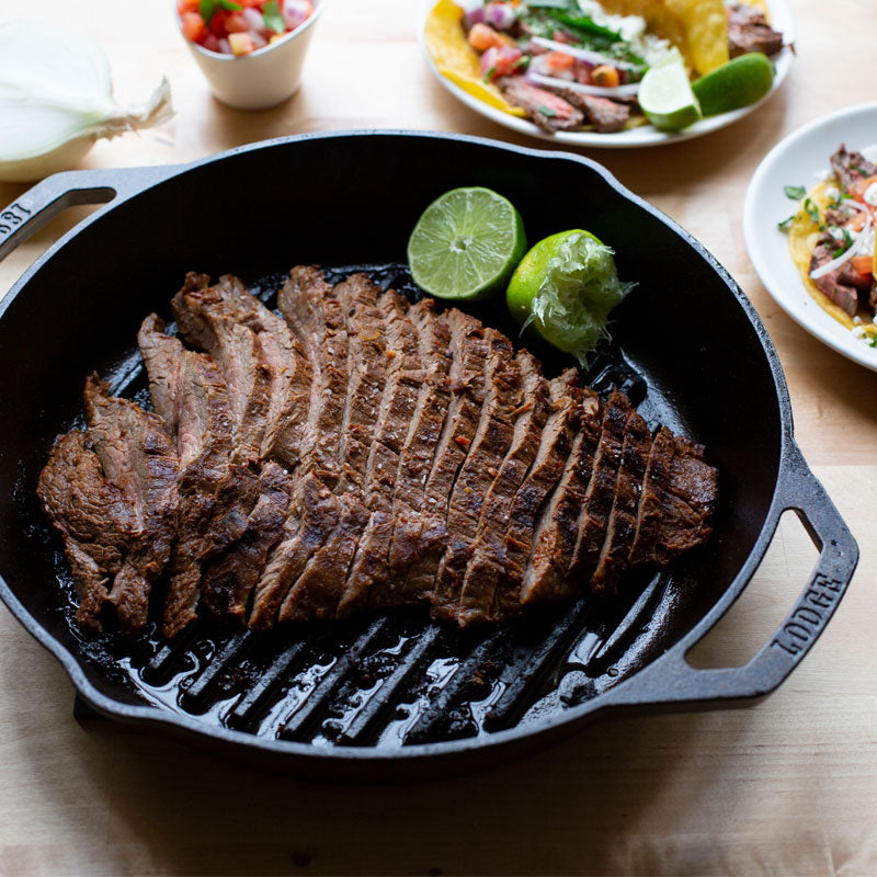 Steak and limes served in grill pan at table.