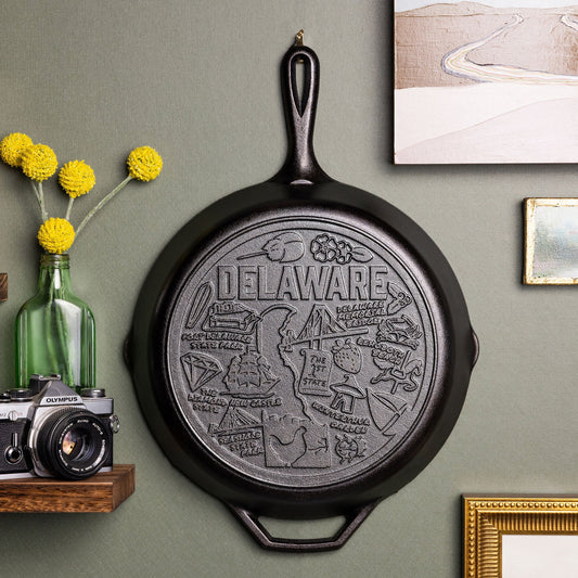 Black cast iron skillet with 'Delaware' engraving on a wall with decorative elements.