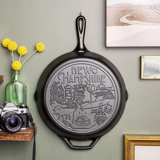 Decorative cast iron skillet with 'New Hampshire' engraving on a wall.