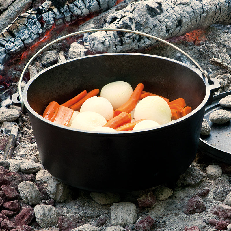 Carrots and onions being cooked near fire.