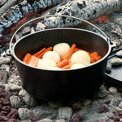 Carrots and onions being cooked near fire.
