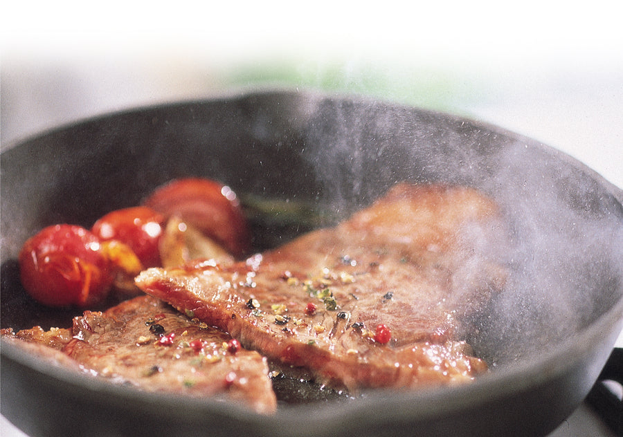 Steak being searing in skillet.