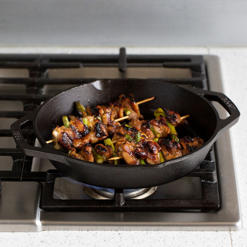 Chicken skewers being cooked on stove with grill pan.