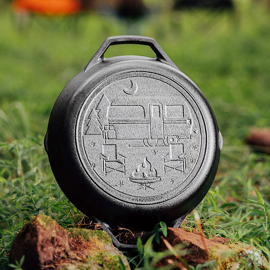 Black cast iron skillet with camping design on a grassy background
