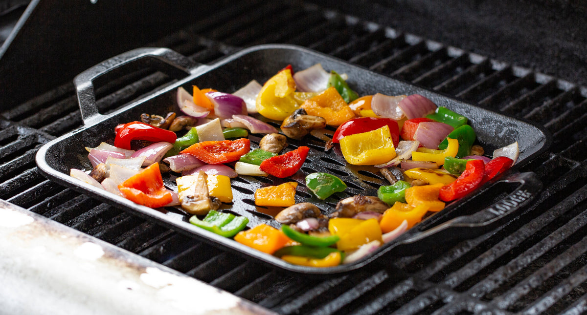 Veggies roasting in grill topper on grill.