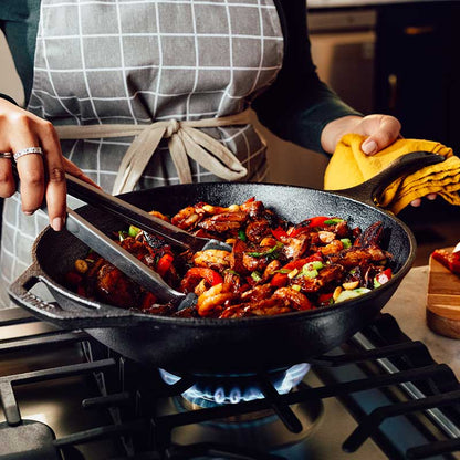 Someone cooking with wok on stovetop.