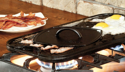 Grill press being used to press bacon while cooking on griddle.