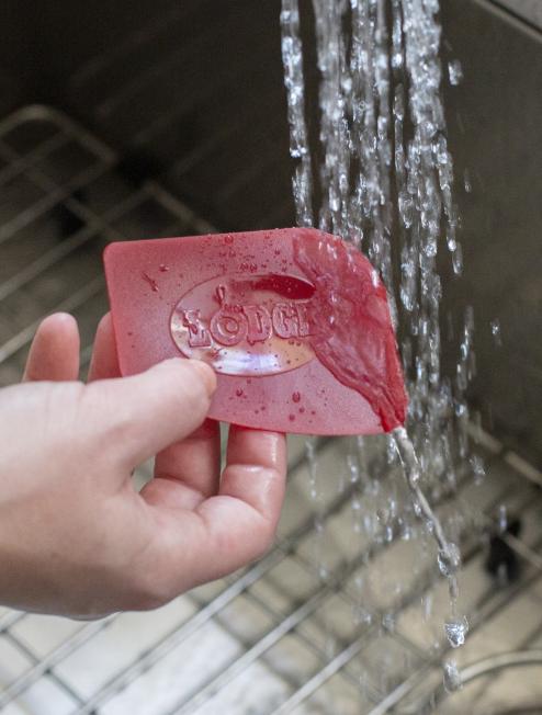 Someone rinsing red scrapper under running water in kitchen sink.
