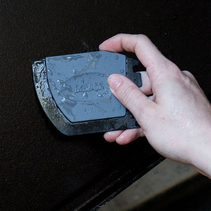 Someone holding scraper near reversible griddle/grill pan.