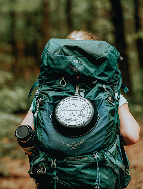 Skillet tied to a camp backpack while someone is on a hike.