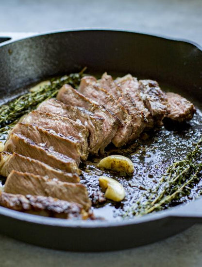 Freshly prepared steak with garlic and rosemary served in pan.