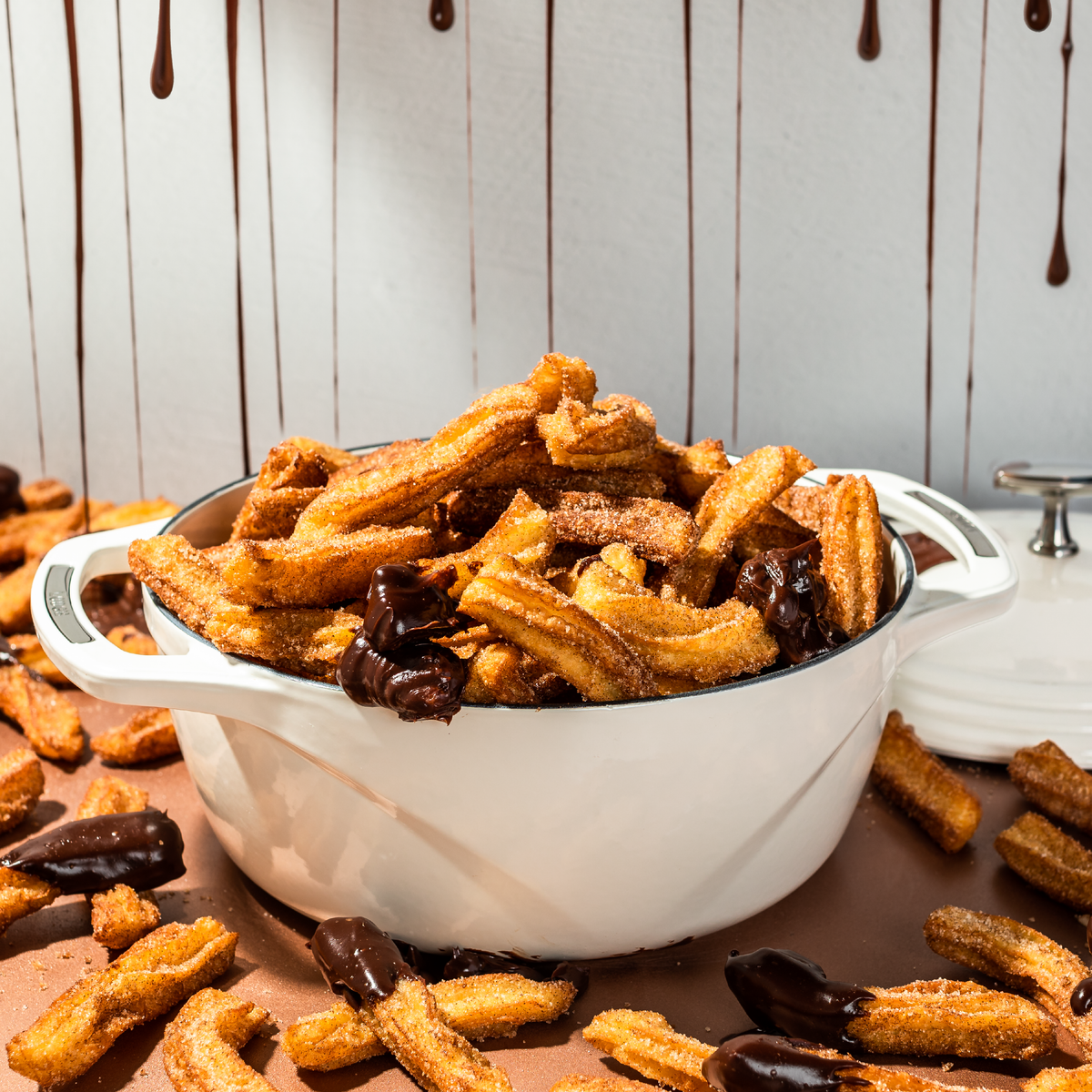 White dutch oven filled with churros and chocolate.