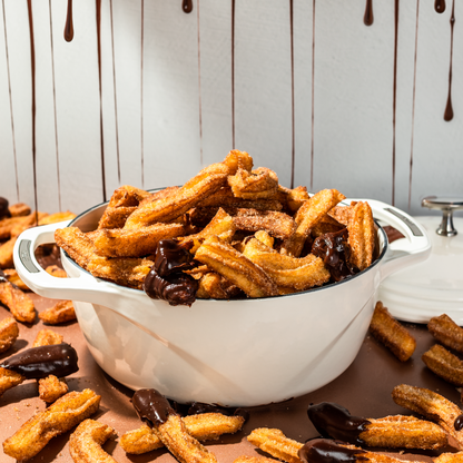 White dutch oven filled with churros and chocolate.