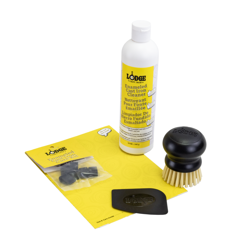 A collection of items for an enameled cast iron and stoneware care kit including a bottle of enamel cleaner, a black scrub brush with stiff bristles, a black pan scraper, and pot protectors.