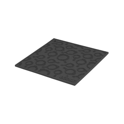 Black silicone trivet with embossed Lodge skillets scattered throughout surface.