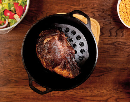 Prime rib roast freshly prepared with skillet and meat rack.