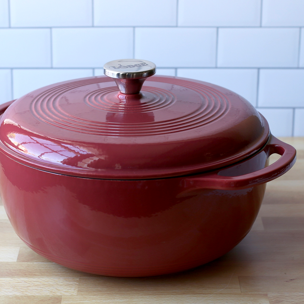 Enameled cast iron Dutch oven with a silver handle on a wooden surface.